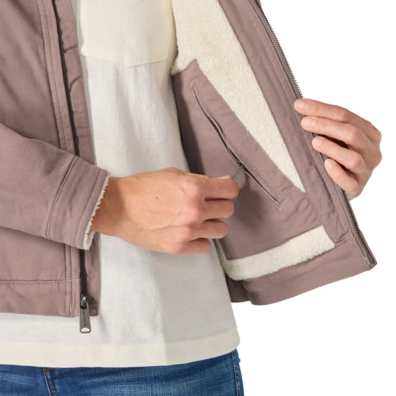 Load image into Gallery viewer, Close-up of a person wearing a taupe-brown jacket with a cream sherpa lining, showing the interior pocket and zipper details.
