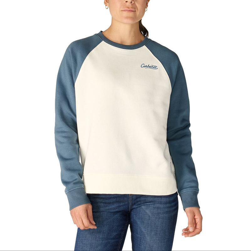 Load image into Gallery viewer, A woman modeling a long-sleeve crewneck sweatshirt with a cream body and slate blue raglan sleeves, featuring a small embroidered 'Carhartt' logo on the left chest, set against a plain white background.
