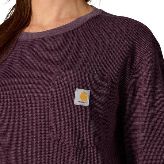 Close-up of a person wearing a textured waffle-knit long-sleeve pocket shirt in a dark plum purple color, featuring a white Carhartt logo patch on the chest pocket.