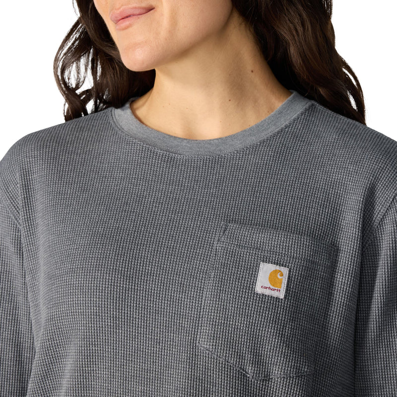 Load image into Gallery viewer, Close-up of a person wearing a dark gray waffle-knit long-sleeve shirt with a chest pocket and a visible Carhartt logo patch.
