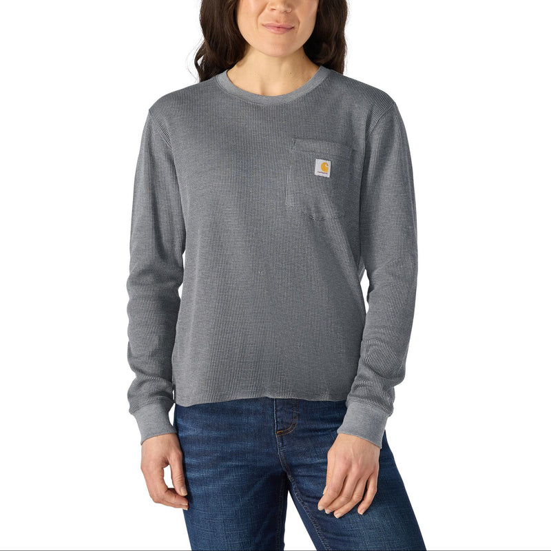 Load image into Gallery viewer, A woman modeling a heather gray long-sleeve crewneck sweatshirt with a small Carhartt logo patch on the left chest, paired with blue jeans against a plain white background.
