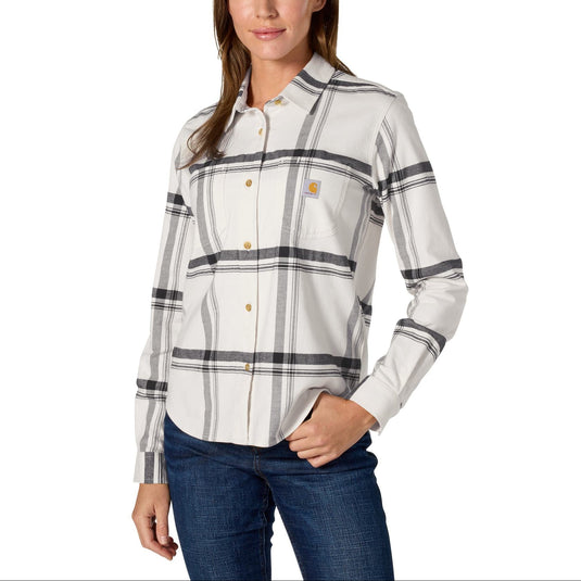 A woman modeling a Carhartt long-sleeve plaid button-down shirt in off-white with gray and black stripes, paired with blue jeans, against a plain white background.
