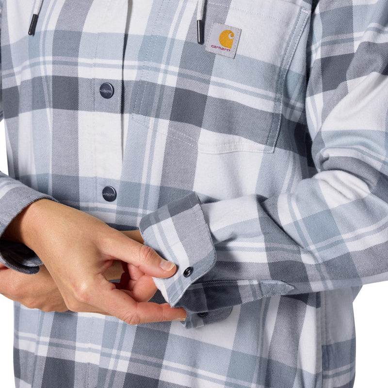Load image into Gallery viewer, Close-up of a person wearing a Carhartt long-sleeve plaid button-up shirt in light gray, white, and blue-gray tones, with hands adjusting the cuff.
