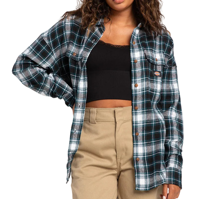 Load image into Gallery viewer, A woman modeling a long-sleeve plaid button-up shirt in black, white, and teal over a black crop top and beige pants, photographed against a plain light gray studio background.
