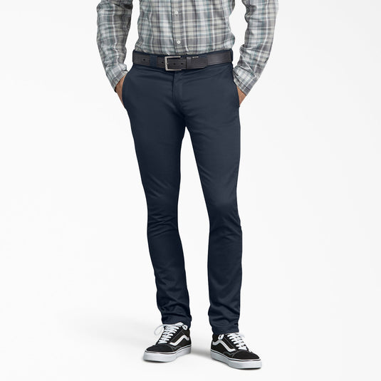 Person wearing navy pants with a plaid shirt and black and white sneakers on a white background