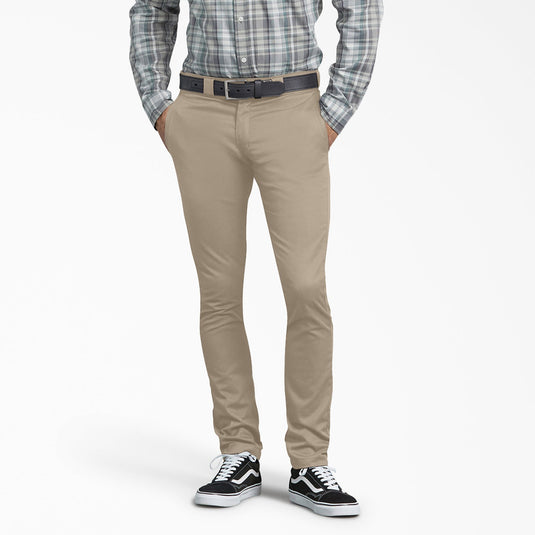 Person wearing beige pants with a plaid shirt and black sneakers on a white background