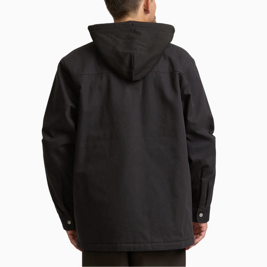 A man viewed from behind wearing a black hooded jacket against a plain white studio background.