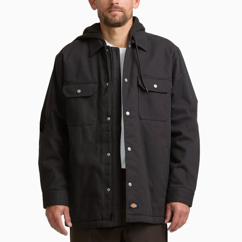 Load image into Gallery viewer, A man wearing a black hooded utility jacket with silver snap buttons and flap pockets, layered over a white t-shirt, photographed against a solid white background.
