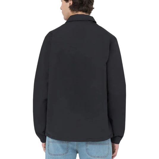 Person wearing a black coaches jacket on a white background