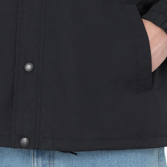 Close-up of a black jacket with button snap closure and light blue jeans.