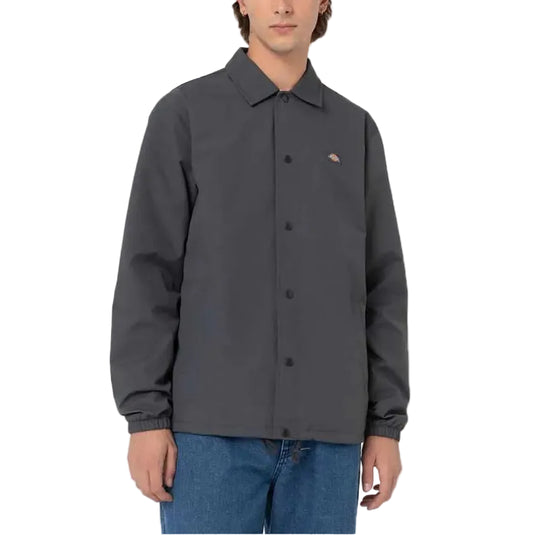 Person wearing a dark gray coaches jacket with a Dickies logo on a white background