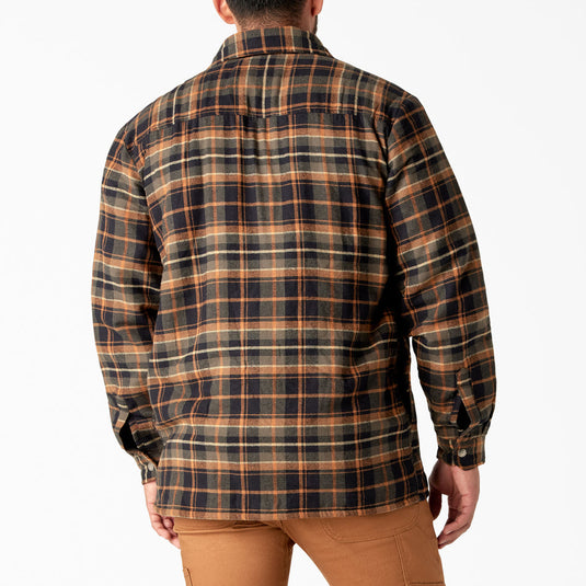 Person wearing a brown and black sherpa lined plaid shirt jacket with a white background