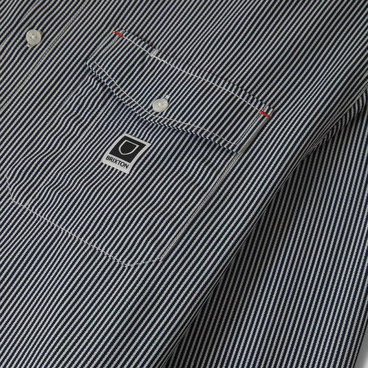 Close-up of a striped shirt with left front button-down flap pockets and a Brixton woven label.