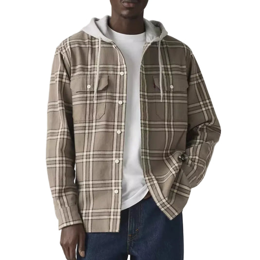 Man wearing a beige plaid shirt over a white t-shirt with a plain background