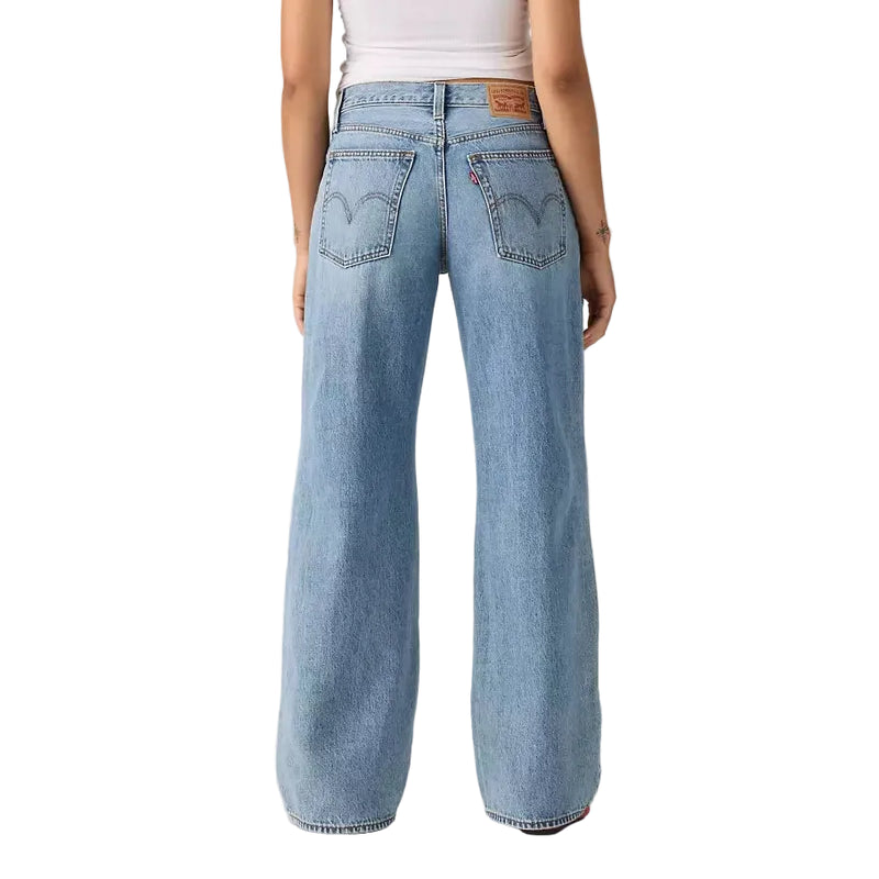 Load image into Gallery viewer, A model shown from the back wearing light-wash wide-leg denim jeans and a white ribbed tank top, photographed against a neutral light gray studio background.
