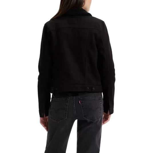 Person wearing a black sherpa lined trucker jacket and washed black jeans on a white background