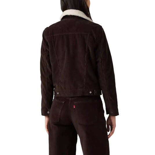 A model shown from the back wearing a dark brown denim jacket with a white shearling collar and matching dark brown corduroy pants against a white studio background.