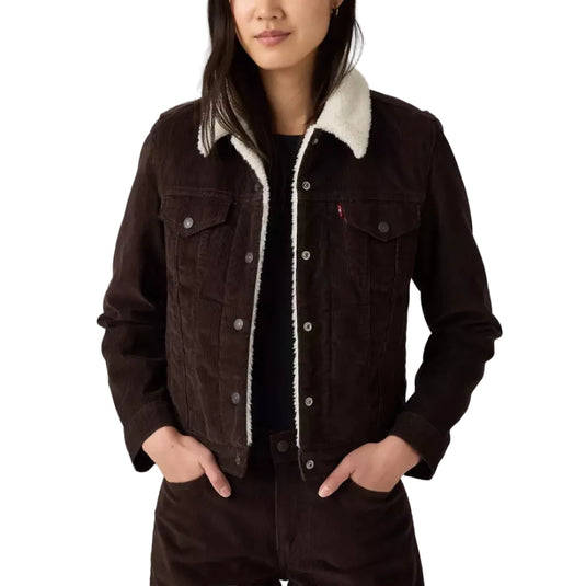 A woman modeling a dark brown denim jacket with a cream sherpa collar, paired with matching dark brown corduroy pants, against a white studio background.
