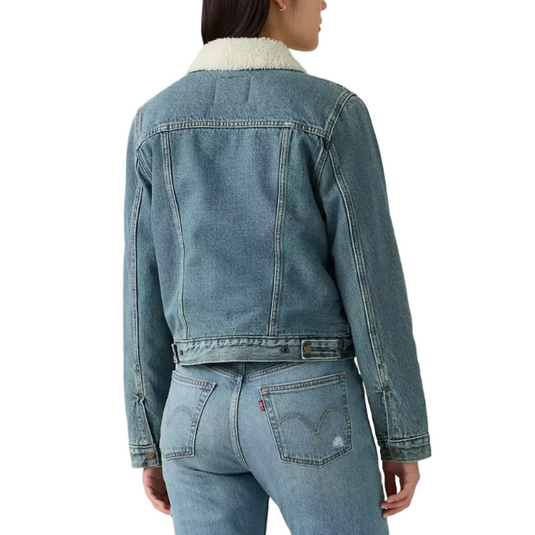 A model shown from the back wearing a cropped light-wash blue denim jacket with a cream sherpa collar, paired with matching light-wash blue jeans, against a plain light gray studio background.