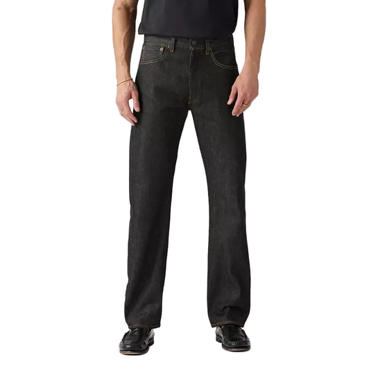 Man wearing a black t-shirt and dark jeans on a gray background