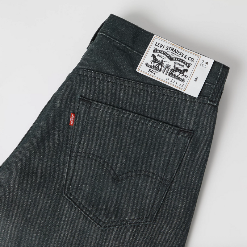 Load image into Gallery viewer, Close-up of the back waistband and pocket area of dark gray Levi's jeans, showing the white Levi's Straws &amp; Co. paper label and the signature red tab.
