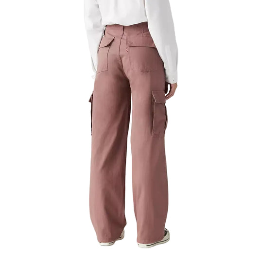 Person wearing pink cargo pants and a white shirt on a plain background