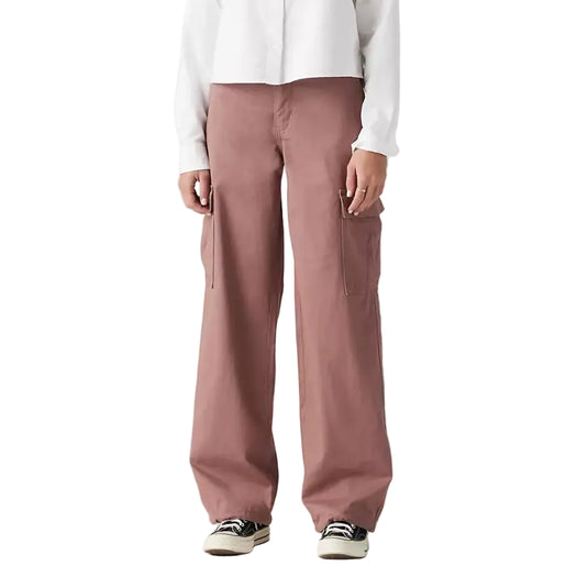 Woman wearing a white jacket and pink pants on a gray background