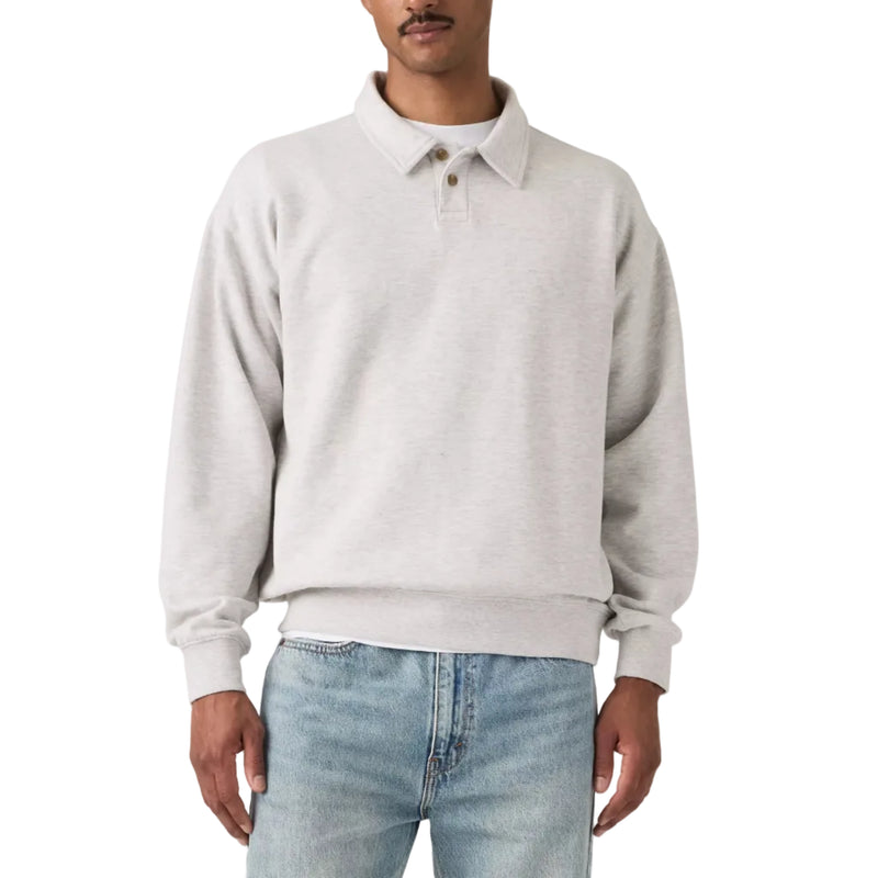 Load image into Gallery viewer, A man wearing a light gray heathered long-sleeve polo sweatshirt and light blue jeans, standing against a neutral light gray studio background.
