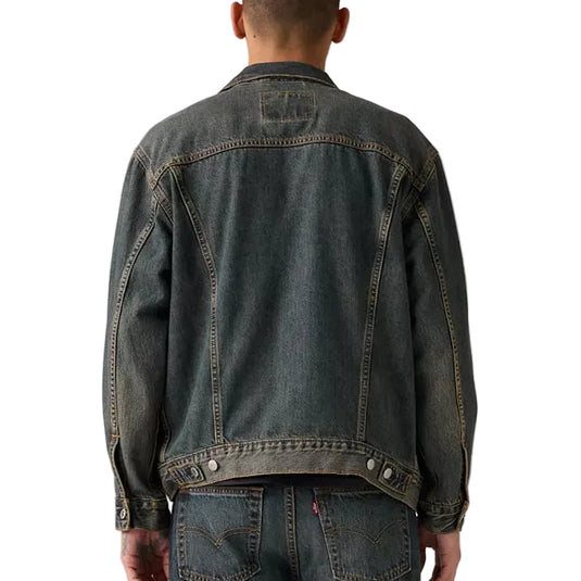 Person wearing a denim jacket and jeans on a plain background