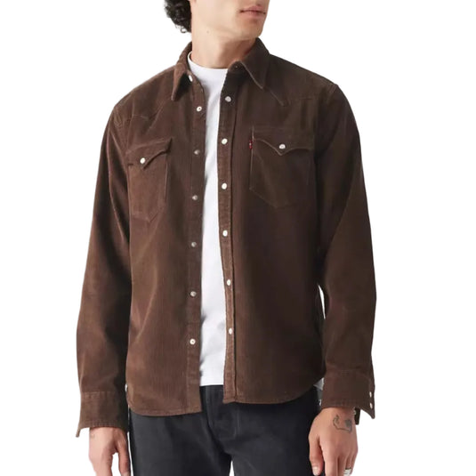 Man wearing a brown corduroy shirt over a white shirt on a plain background