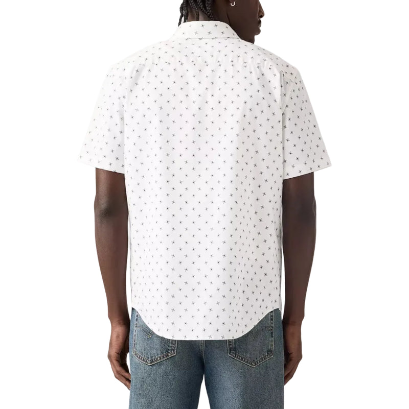 Load image into Gallery viewer, A man viewed from the back wearing a white short-sleeve button-up shirt with a small black geometric pattern, paired with blue jeans, against a light gray studio background.

