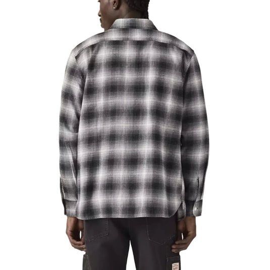 Person wearing a black and white plaid shirt on a plain background