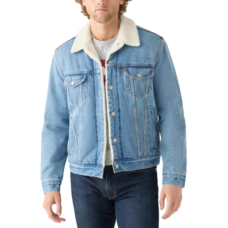 Load image into Gallery viewer, A man wearing a light blue denim trucker jacket with a cream sherpa collar, layered over a white t-shirt and dark blue jeans, against a plain white background.
