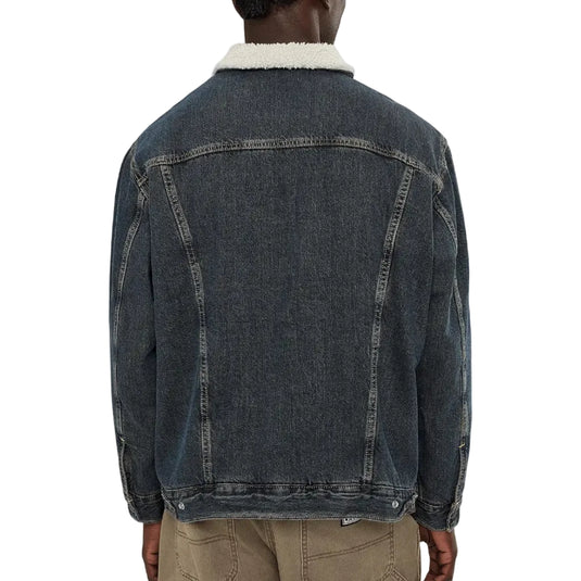 A person shown from the back wearing a dark washed denim jacket with a white sherpa collar, paired with tan pants, against a plain white background.