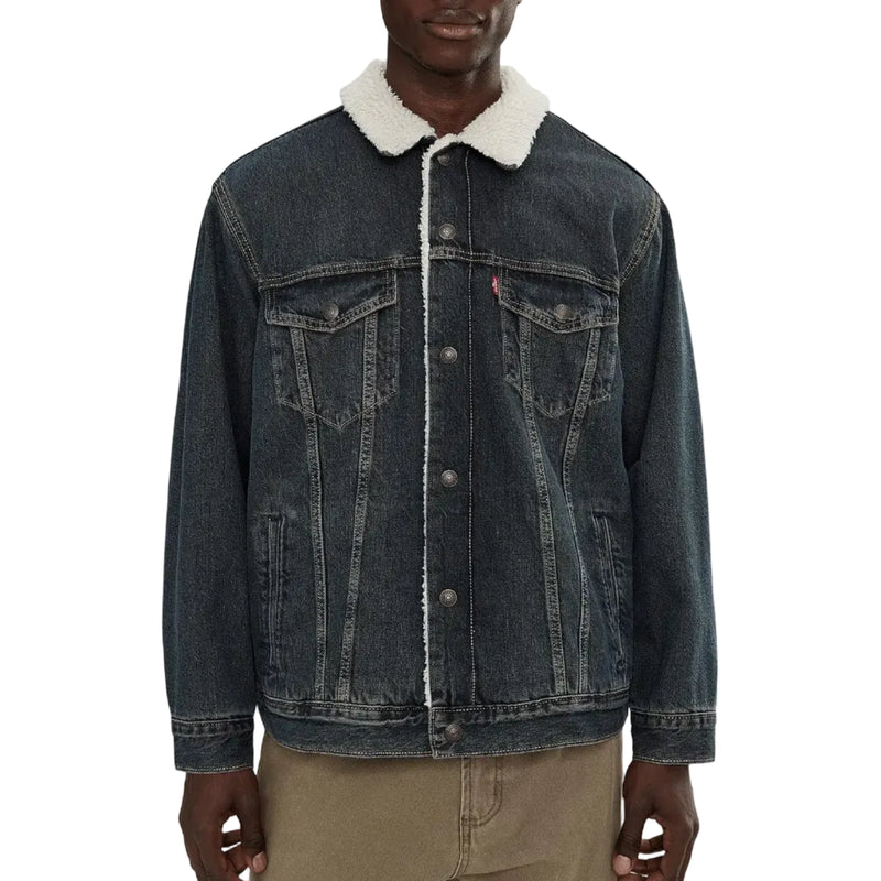Load image into Gallery viewer, A man wearing a dark blue denim trucker jacket with a white sherpa fleece collar, paired with khaki pants, against a plain white background.
