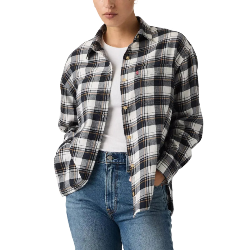 Load image into Gallery viewer, A woman modeling a black and white plaid button-up shirt over a white t-shirt and blue jeans, photographed against a solid light gray background.
