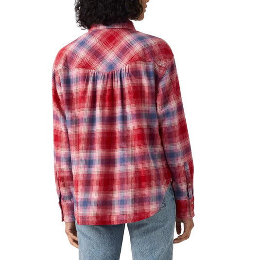 A model shown from the back wearing a red, blue, and white plaid button-down shirt and light blue jeans against a plain light gray background.