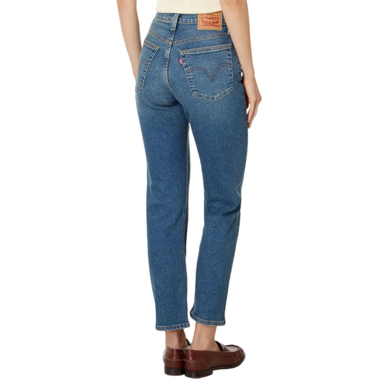 Rear view of a model wearing Levi's straight-leg blue jeans with brown leather loafers, on a white background.