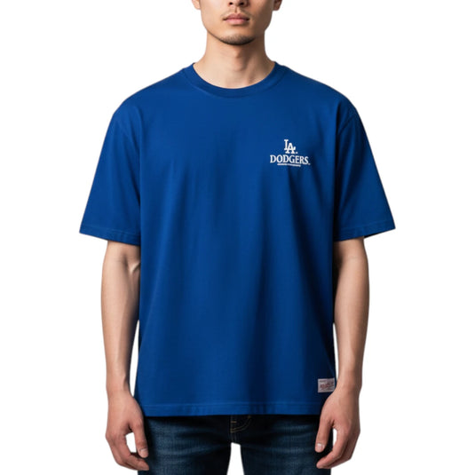 A man wearing a royal blue Los Angeles Dodgers t-shirt with a white embroidered logo on the left chest, paired with dark blue jeans, against a plain white background.