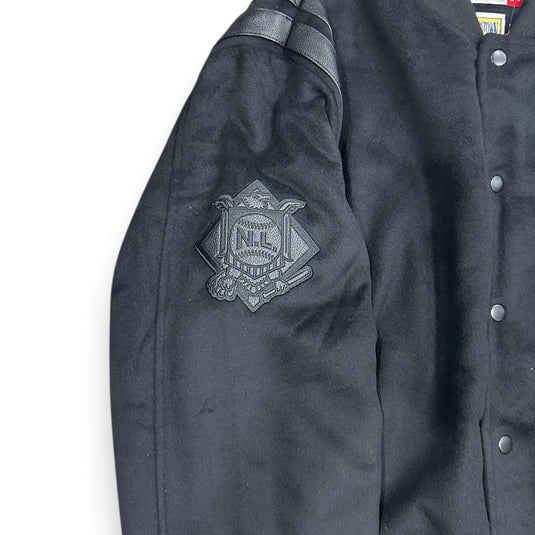 Close-up of a black varsity jackets sleeve with a black patch on a white background. 