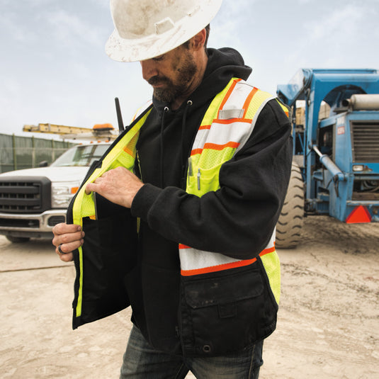 Person in safety vest that highlights the inner pocket details on the Kishigo 1515 lime colored premium black series vest.