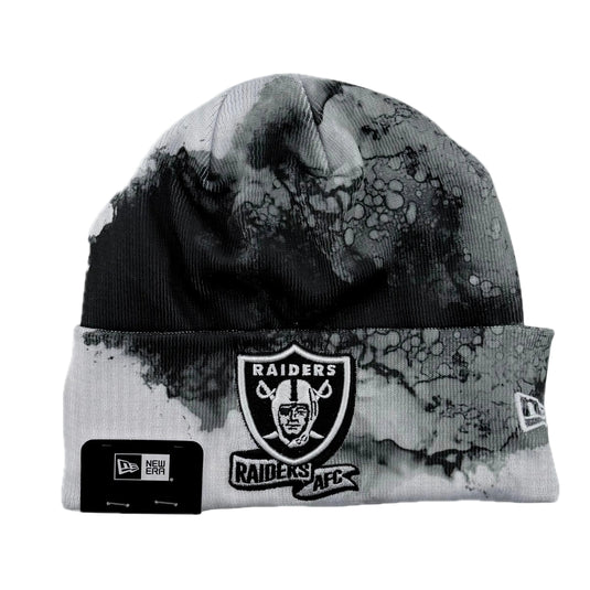 Knit beanie with NFL Raiders logo on a white beanie with printed black, gray and white ink design in background. 