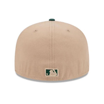 A structured baseball cap in a light tan/beige color, featuring a small green and white MLB logo patch on the front and a dark green top button, shown against a plain white background.