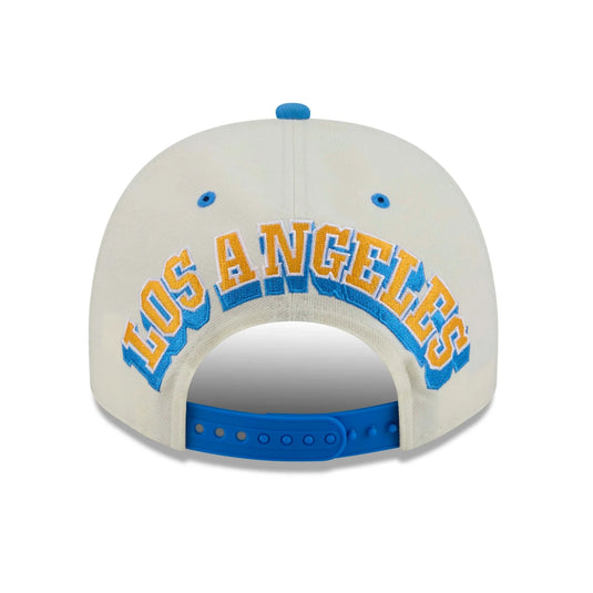 A white baseball cap viewed from the back, featuring 'LOS ANGELES' in arched yellow letters with blue outlines and a blue snapback strap.