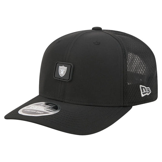 A black trucker-style baseball cap with a structured front panel, black mesh back, a Raiders patch on the front, and a white New Era logo on the side, shown on a plain white background.