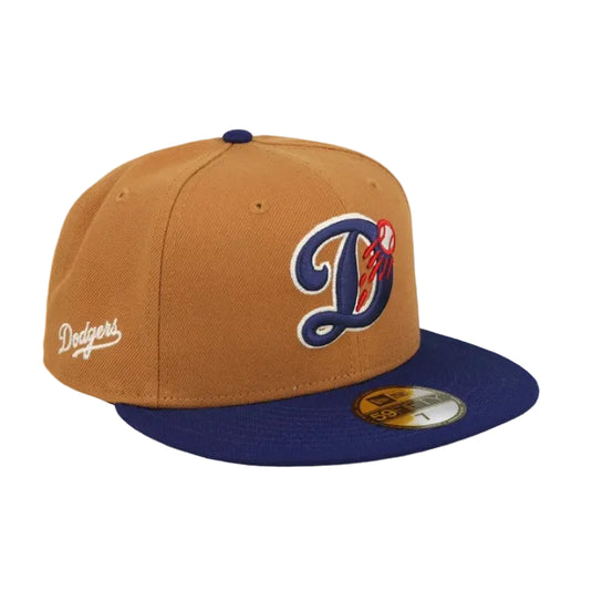 A Los Angeles Dodgers fitted baseball cap featuring a camel brown crown, a navy blue flat brim, and a navy blue embroidered 'D' logo with a red and white flame detail on the front. The left side of the cap displays the white embroidered 'Dodgers' script logo, and a gold New Era 59FIFTY sticker is visible on the brim.