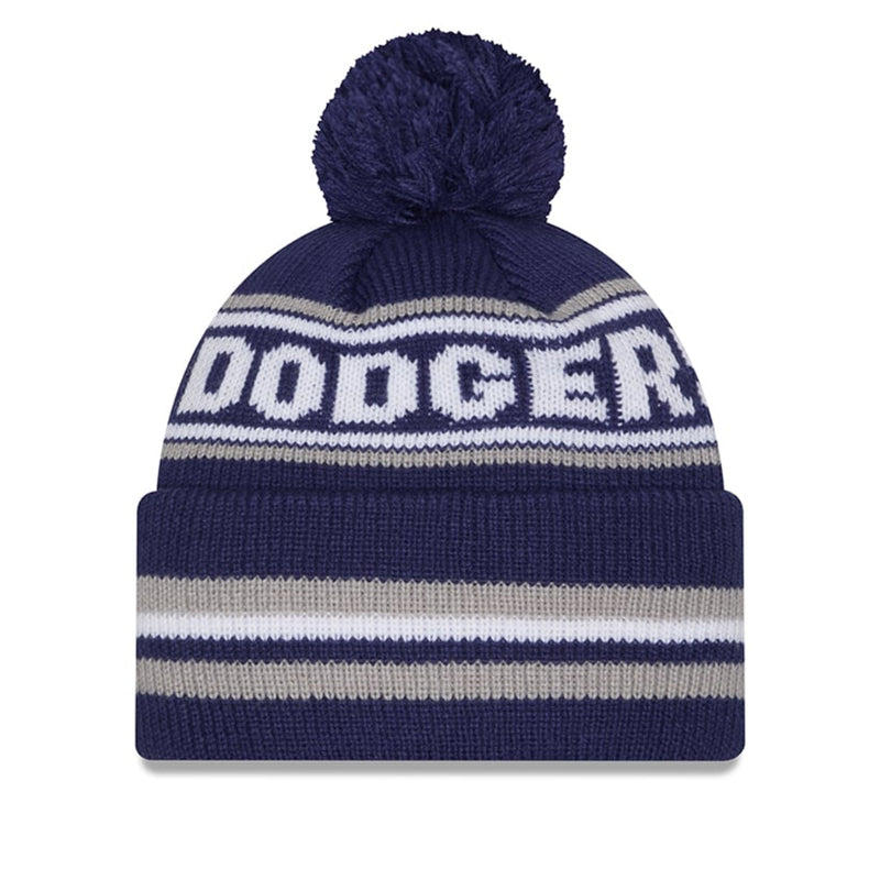 Load image into Gallery viewer, A navy blue knit pom-pom beanie with white and gray stripes and the word 'DODGERS' knitted across the front, shown on a plain white background.
