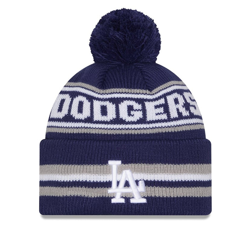 Load image into Gallery viewer, A navy blue knit pom-pom beanie with white and gray stripes, featuring the word 'DODGERS' across the top and the 'LA' Dodgers logo on the front cuff.
