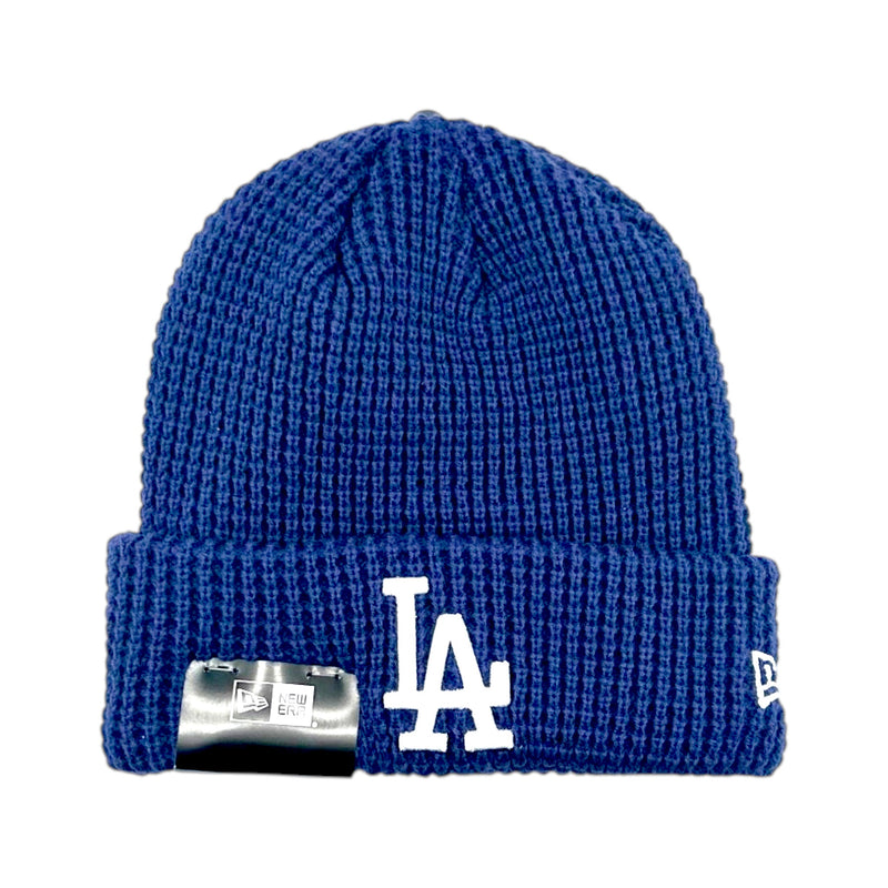 Load image into Gallery viewer, A royal blue ribbed knit beanie hat featuring a white embroidered 'LA' logo on the front cuff and a silver metal tag on the side, photographed against a solid white background.
