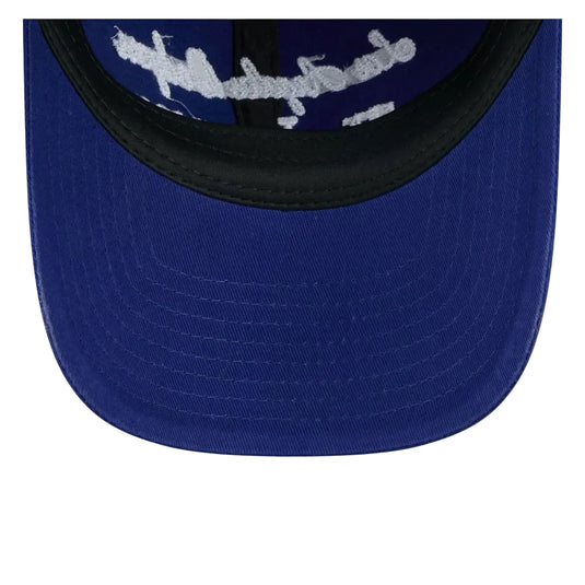 Close-up of the front panel of a royal blue baseball cap with a black curved brim and a white embroidered graphic across the top.